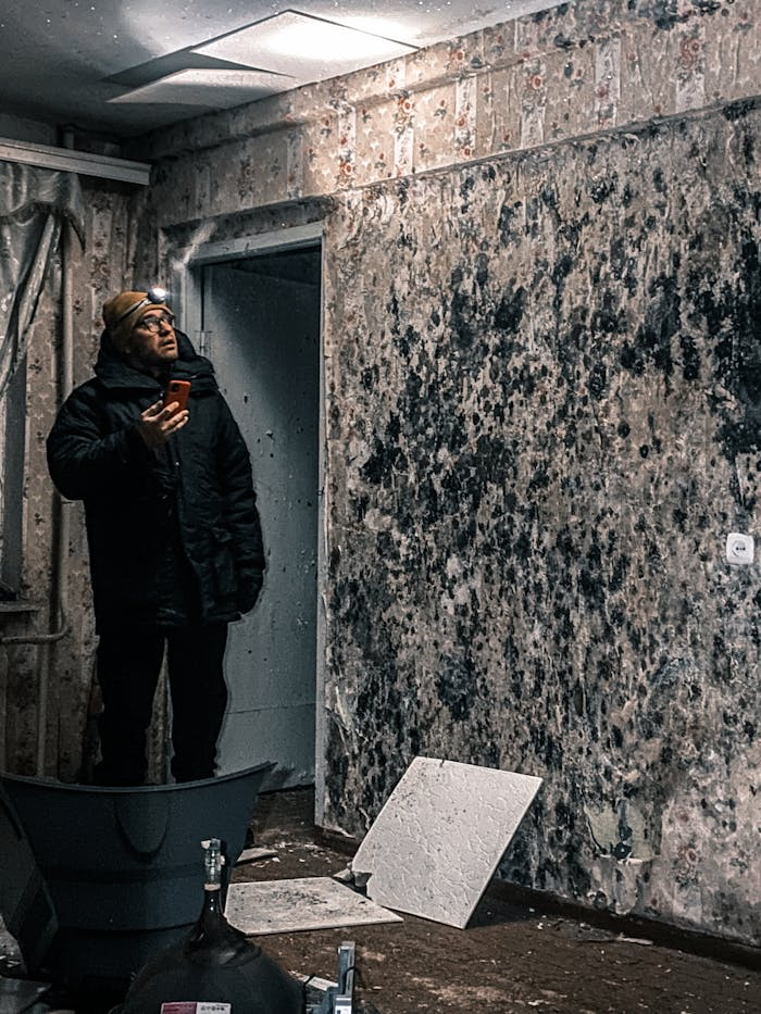 about-02 Man with flashlight inspects mold-covered walls in an abandoned building in Vorkuta, Russia.